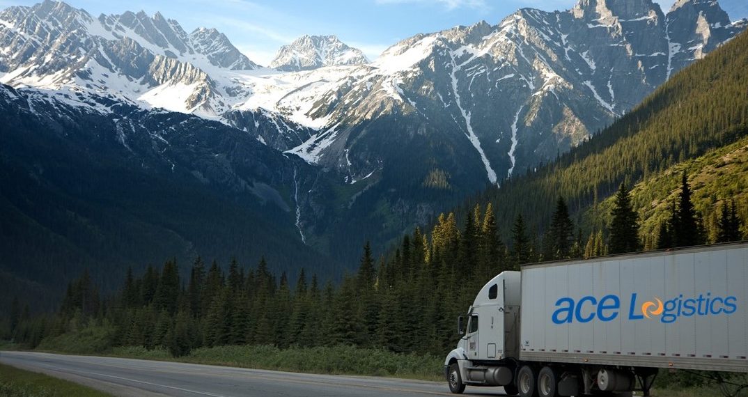 ace Logistics auto kravu pārvadājumi ar logo uz auto piekabes sāna, fonā kalni